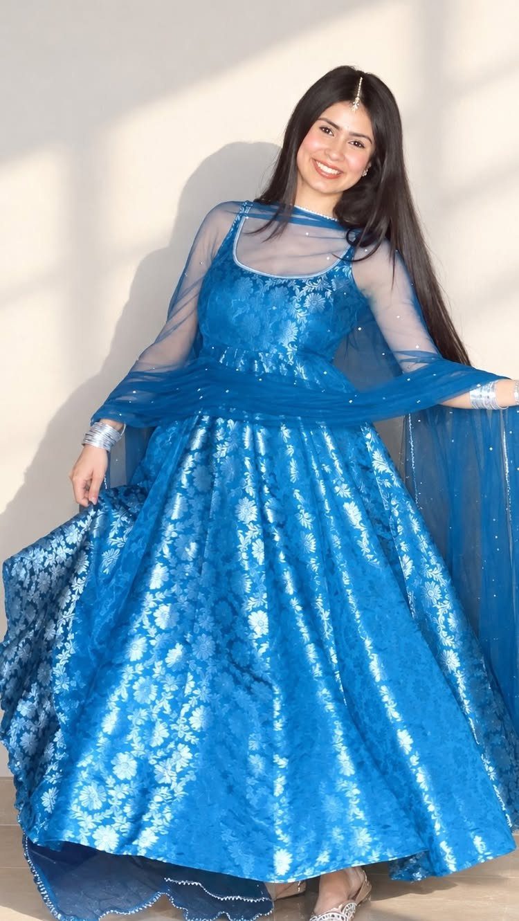 Woman wearing a shimmering blue Anarkali suit with a matching sheer dupatta.