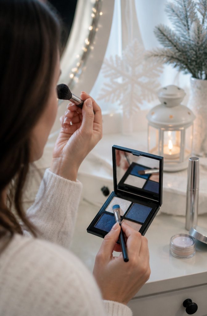 Model applying cerulean blue eyeshadow with a flat brush.