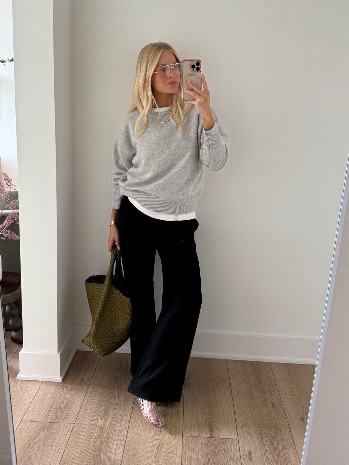 Woman wearing a grey sweater and black wide-leg athletic pants with a green tote.