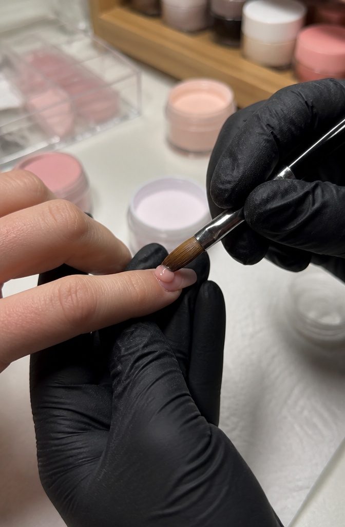 Acrylic Nail Extensions for Short Nails: 10 Steps for 2026 7 Close-up of a hand applying an acrylic bead onto a short nail.