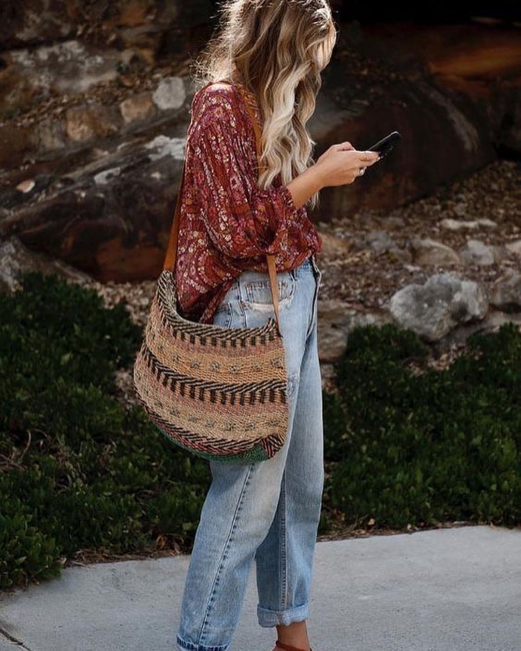 Palazzo Jeans Outfit for Women: 7 Ways to Wear Them 2 Woman in a red boho blouse and wide-leg jeans carrying a woven bag.