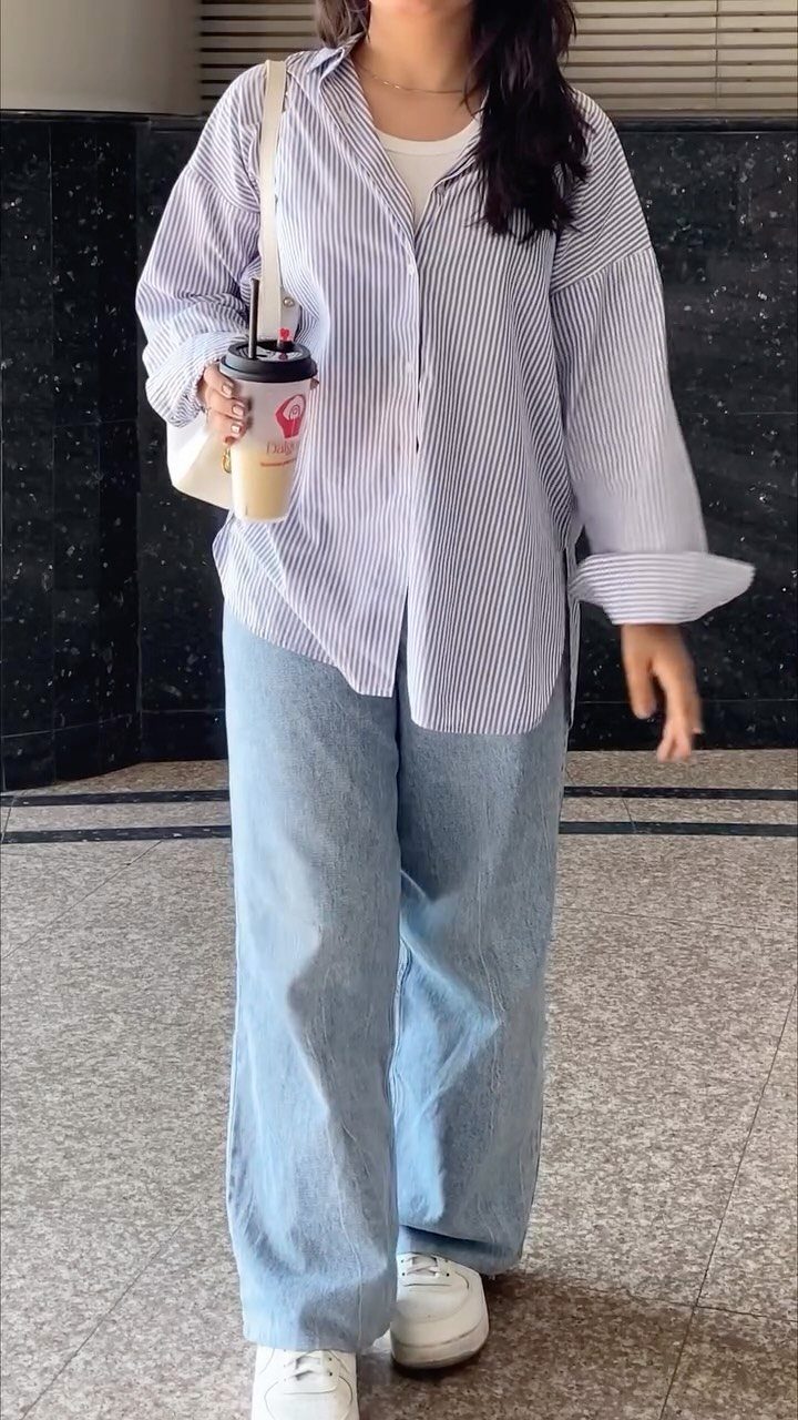 Palazzo Jeans Outfit for Women: 7 Ways to Wear Them 4 Woman in striped shirt and wide-leg palazzo jeans wearing white sneakers holding coffee