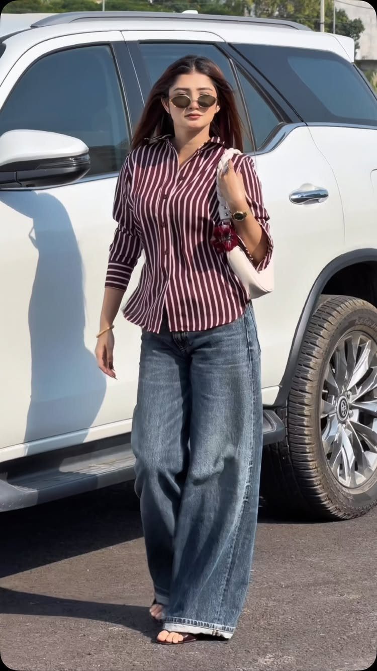 Palazzo Jeans Outfit for Women: 7 Ways to Wear Them 8 Woman in striped shirt and wide-leg blue palazzo jeans standing by white car