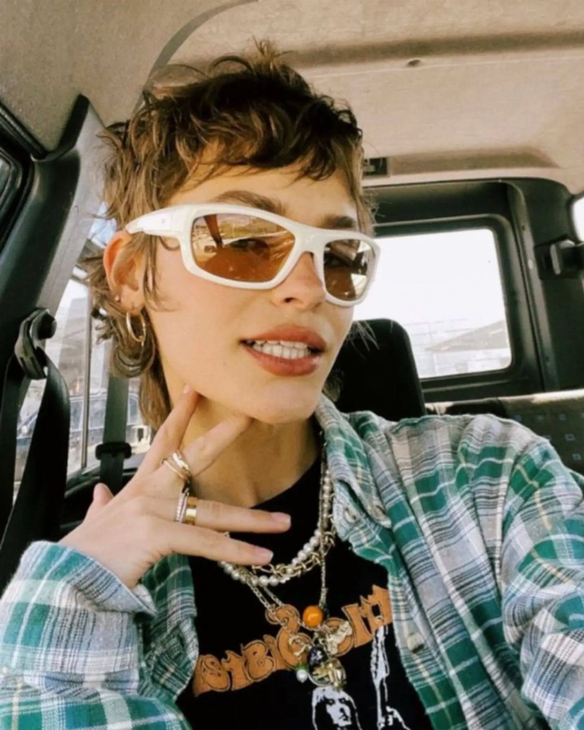19 Short Pixie Cuts Over 40 With Styling and Color Tips 4 Woman with a choppy brown pixie cut wearing white sunglasses in a car.