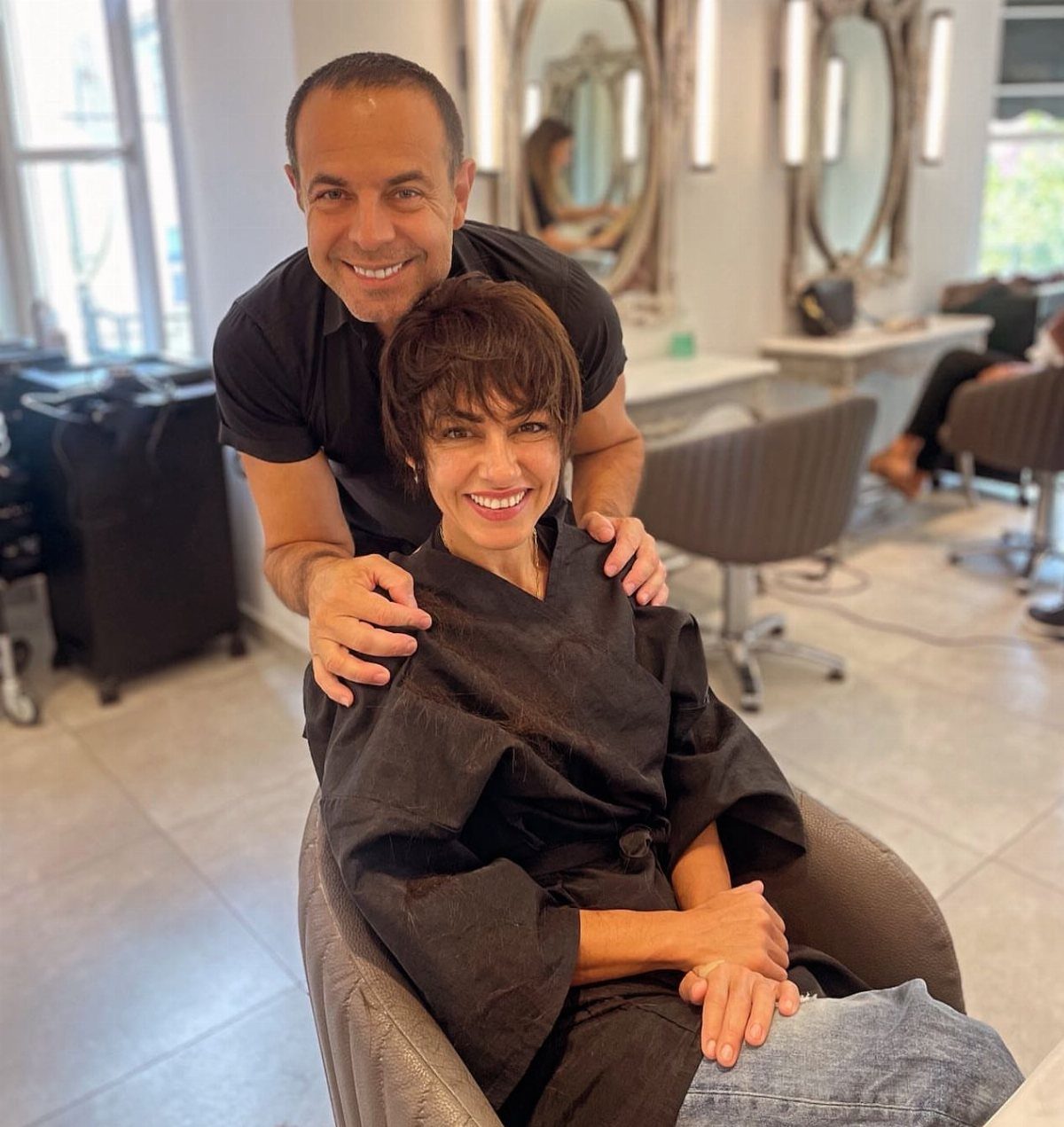 19 Short Pixie Cuts Over 40 With Styling and Color Tips 2 Woman with a brown pixie cut and long bangs posing with her stylist.