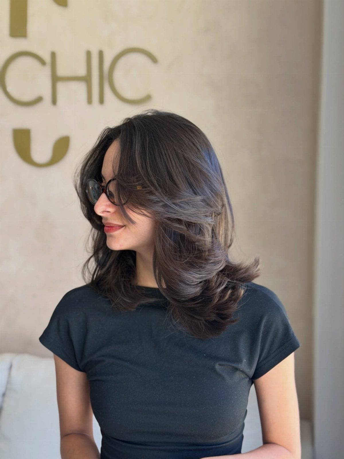 16 Shoulder Length Layered Hair Ideas for Every Texture 3 Woman with dark brown shoulder-length hair styled in a voluminous butterfly cut.