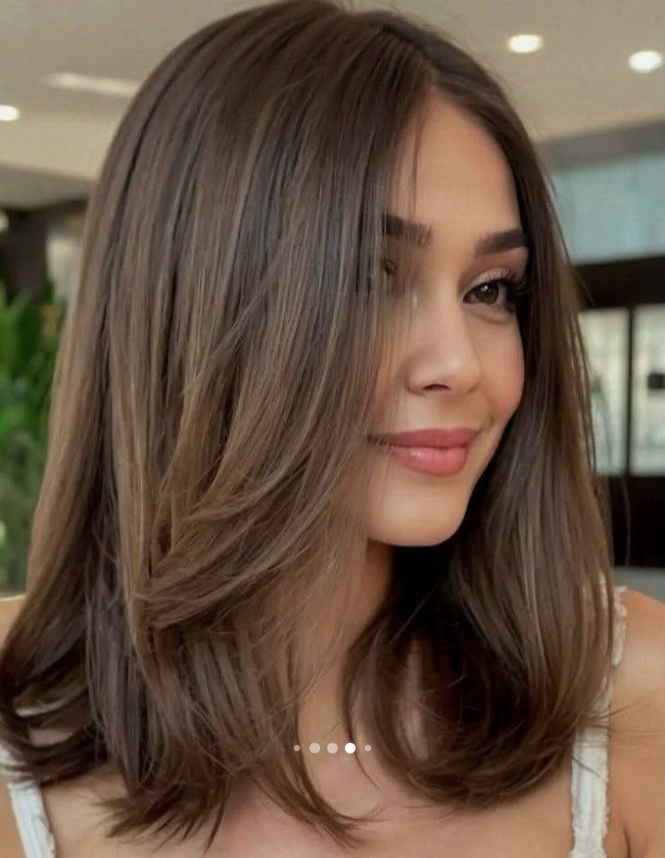 16 Shoulder Length Layered Hair Ideas for Every Texture 17 Woman with brown shoulder length layered hair and a middle part smiling.