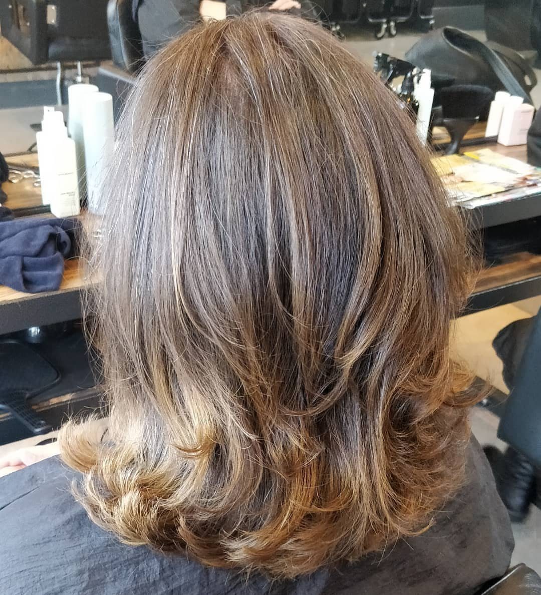 16 Shoulder Length Layered Hair Ideas for Every Texture 2 Shoulder-length brown hair with textured layers and curled ends in a salon setting.