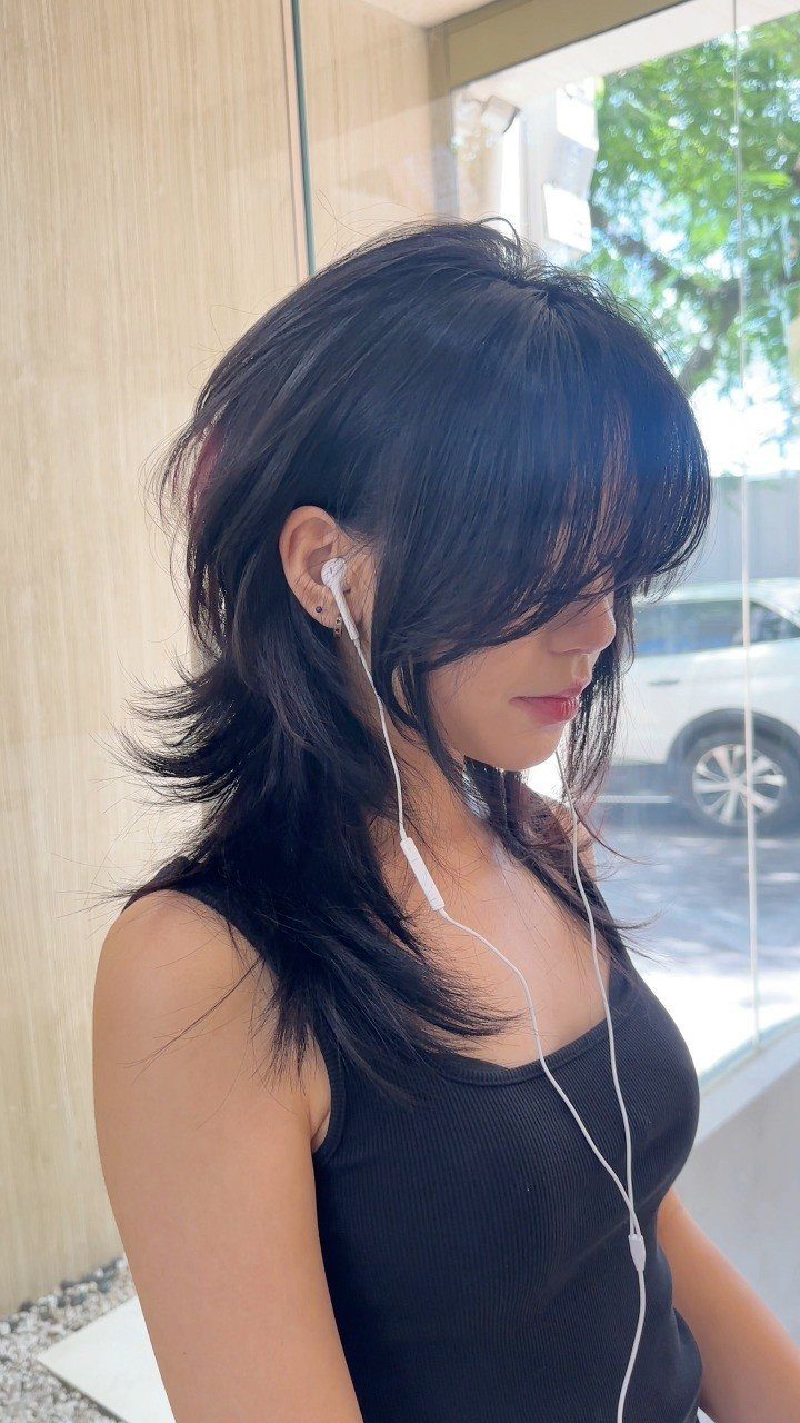 16 Shoulder Length Layered Hair Ideas for Every Texture 14 Woman with a dark wolf cut hairstyle featuring shaggy layers and long bangs.